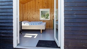 A small wooden cabin with a single bed, a window, and a hanging light fixture. - Serene Holiday Home in Jutland near Sea (Thisted)