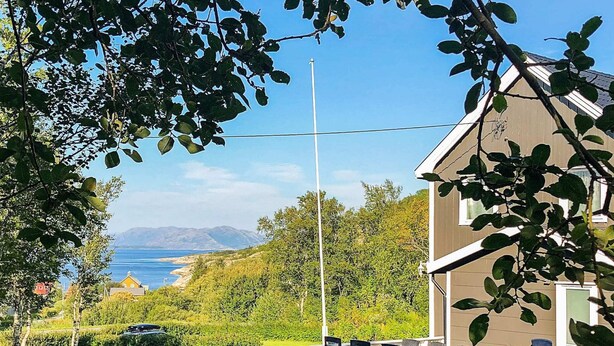 A house with a white porch, a flagpole, and a view of the sea and mountains. - 6 Person Holiday Home in Vevelstad (Vevelstad)