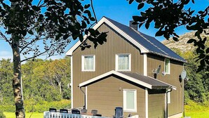 A two-story house with a balcony, surrounded by greenery and a clear sky. - 6 Person Holiday Home in Vevelstad (Vevelstad)