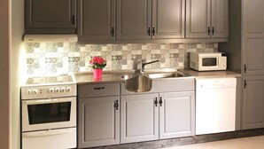 A kitchen with grey cabinets, a white stove, a sink, and a microwave. - 6 Person Holiday Home in Vevelstad (Vevelstad)