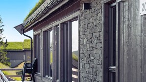 Un bâtiment doté d’une façade en pierre, de grandes fenêtres et d’une terrasse en bois.