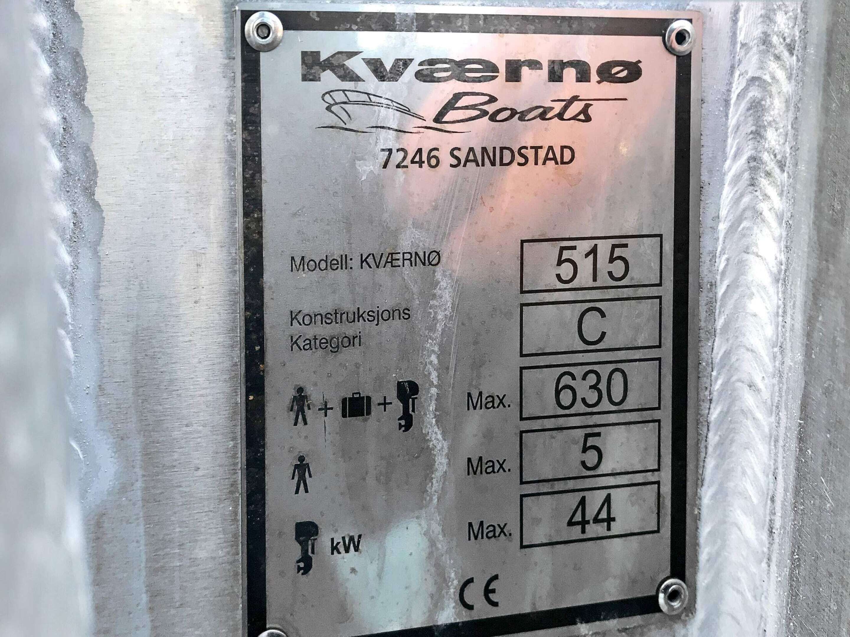 Een metalen plaquette met de tekst 'Kvaerno Boats' en '7246 Sandstad', model 'KVAERNO', constructiecategorie 'C' en maximale capaciteit '630', met de cijfers '5' en '44'.