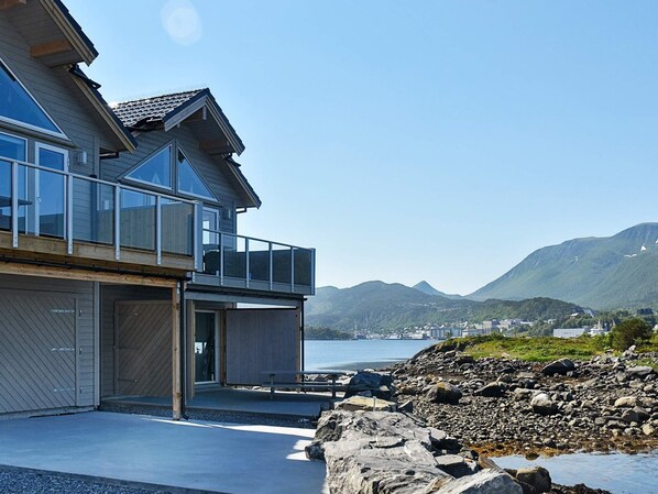 Ein modernes Haus mit einem Balkon mit Blick auf eine felsige Küstenlinie und ein Gewässer.