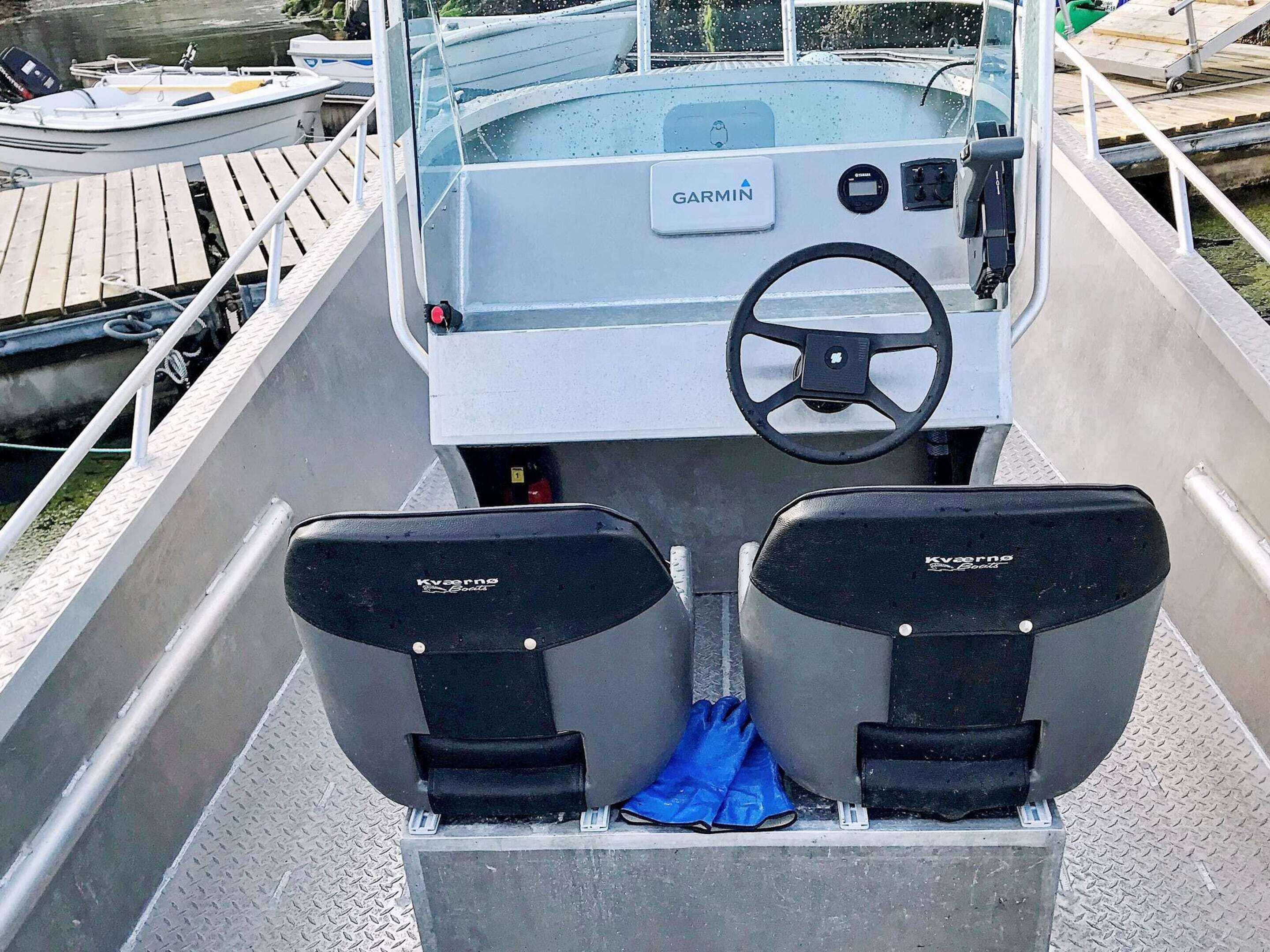 A boat's interior with a Garmin navigation system, two Kverneland boats seats, and a steering wheel.