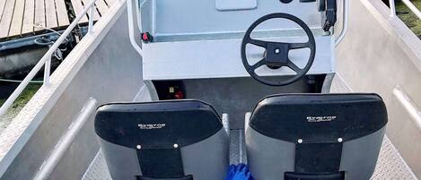 A boat's interior with a Garmin navigation system, two Kverneland boats seats, and a steering wheel.