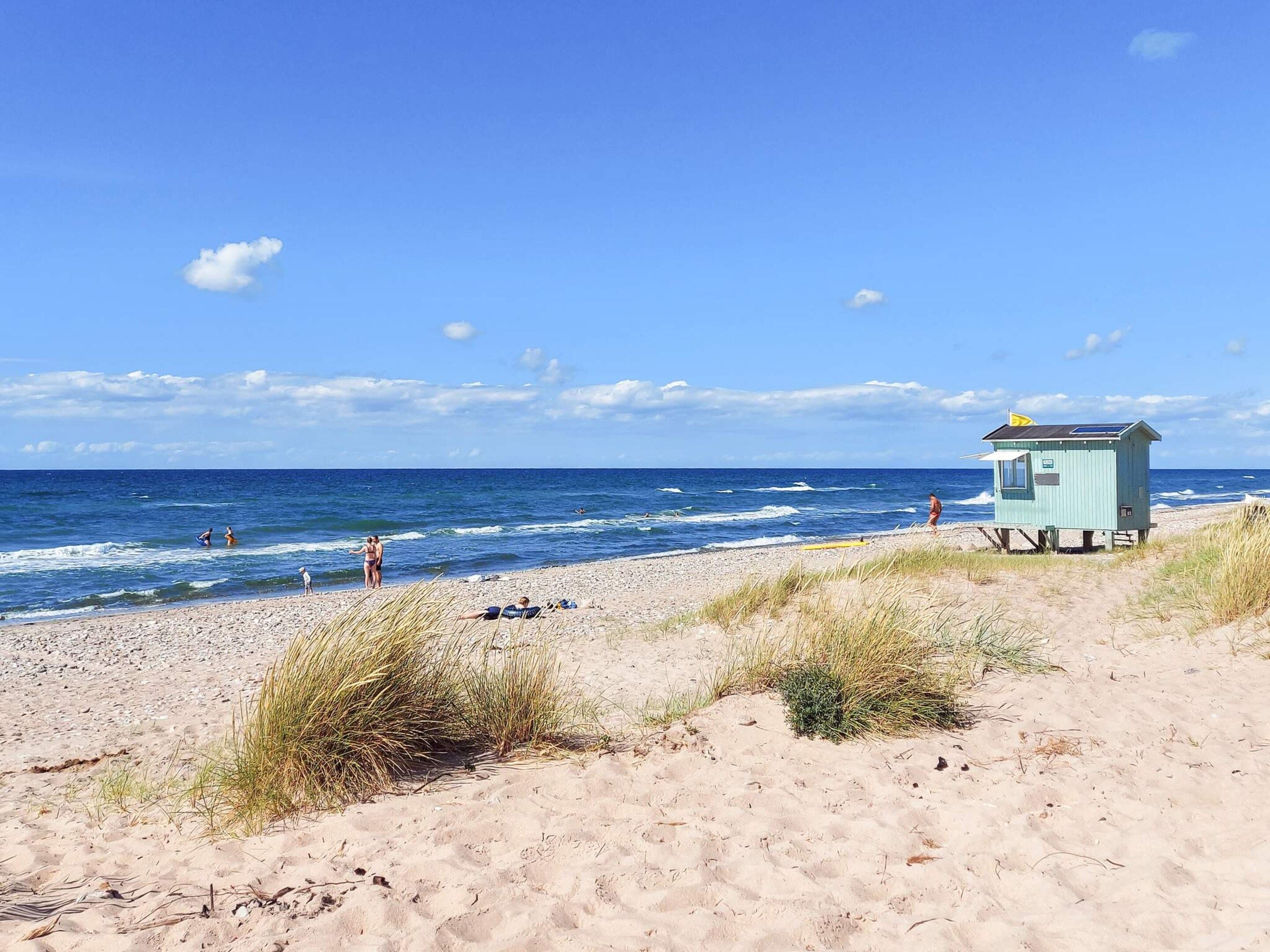 Ein Strand mit einer Rettungswache, Sanddünen und dem Meer.