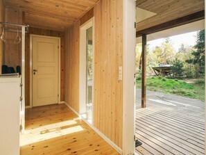 Un couloir intérieur en bois mène à une terrasse offrant une vue sur l’extérieur.