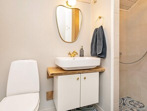 Een badkamer met een wit wastafel, een gouden kraan en een spiegel met een gouden lijst.