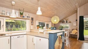 A modern kitchen with wooden cabinets, a central island, and a view of the outdoors. - Spacious Holiday Home in Jutland With Outdoor Whirlpool (Pandrup)
