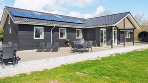 Moderni talo, jossa on aurinkopaneelit, katettu terassi ja ulkotila istumista varten.