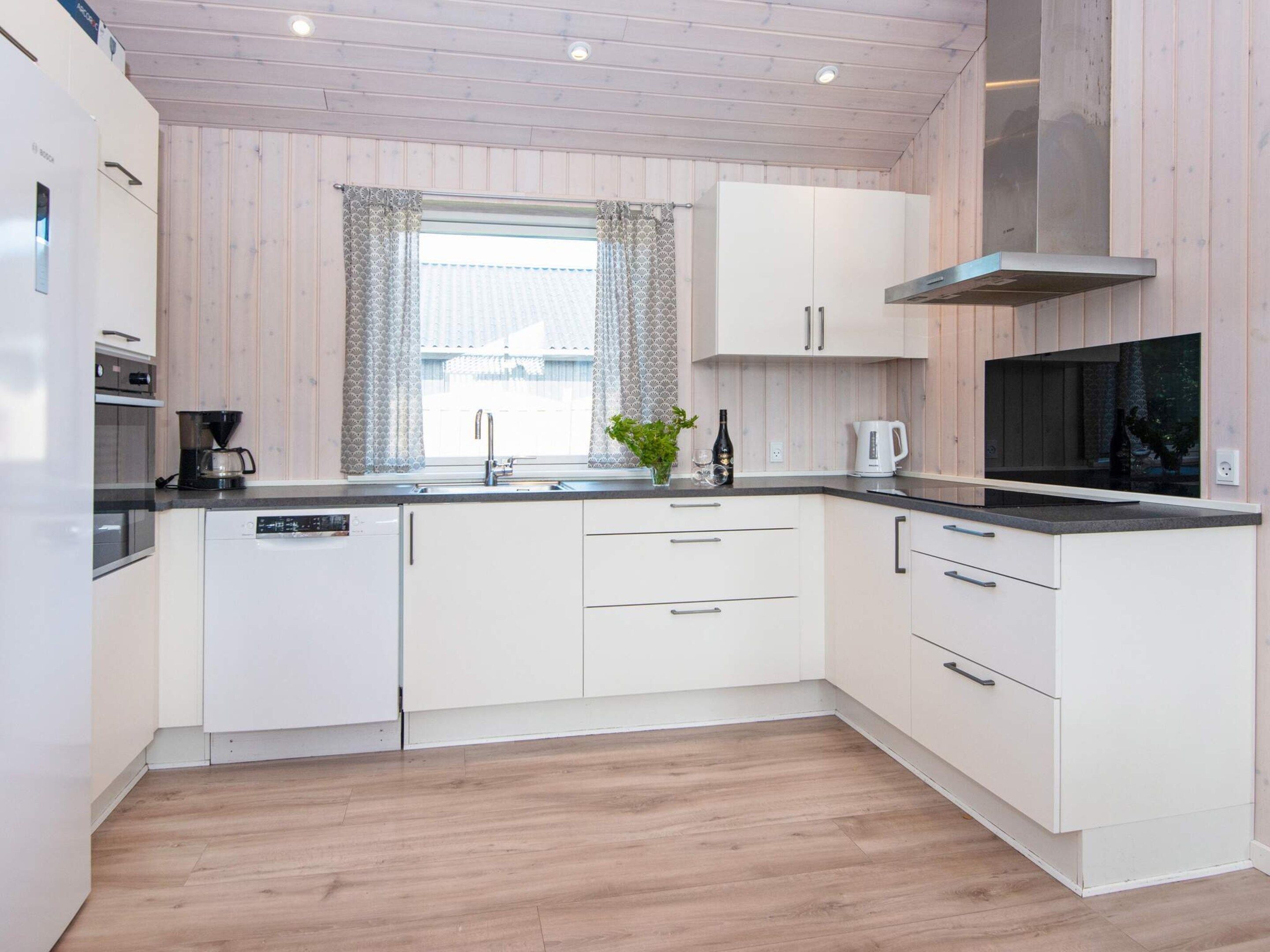 A modern kitchen with white cabinets, a stainless steel sink, and a black countertop.