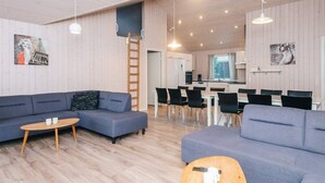Moderni olohuone, jossa on sohva, sohvapöytä ja ruokailutila.