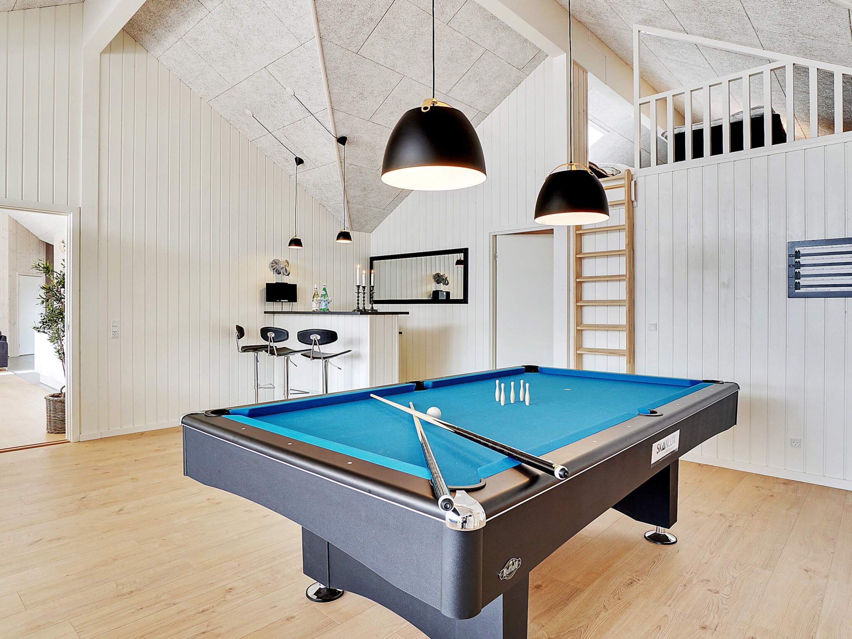 A pool table with a blue felt surface, a billiard cue, and a cue rack.