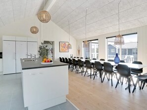A modern kitchen with white cabinets, a central island, and a dining area with black chairs and a large table.