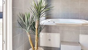 A modern bathroom with a bathtub, a shower, and a potted plant. - 5 Star Holiday Home in Grenaa (Grenaa)