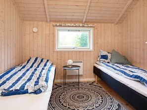 A room with two beds, a small table, and a window with a view of greenery. - Picturesque Holiday Home in Hovedstaden With Sauna (Vejby)
