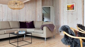 Ein gemütliches Wohnzimmer mit einer Couch, einem Couchtisch und einem Korbstuhl.