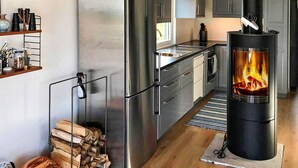 A modern kitchen with stainless steel appliances, a wood-burning stove, and a rustic wooden floor. - 4 Star Holiday Home in Akersberga (Akersberga)
