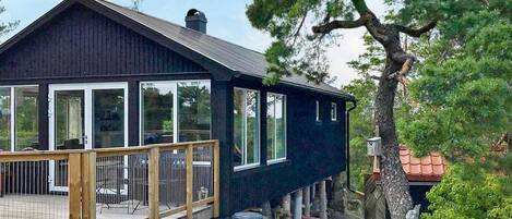 A two-story house with a wooden deck and large windows.