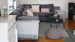 A modern living room with a grey sofa, a white side table, a black coffee table, and a grey rug.