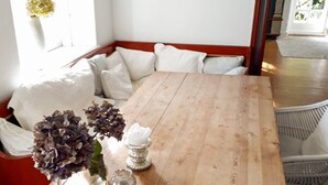 A dining area with a wooden table, white chairs, and a vase with flowers.