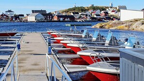 A harbor with boats docked at a pier, a lighthouse in the background, and buildings along the shore. - 4 Person Holiday Home in Sula (Frøya)