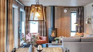 A cozy living room with a fireplace, a dining area with a wooden table, and a sofa. - 4 Star Holiday Home in Favang (Ringebu)