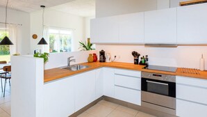 A modern kitchen with white cabinets, stainless steel appliances, and a wooden countertop. - 5 Star Holiday Home in Lokken (Lokken)