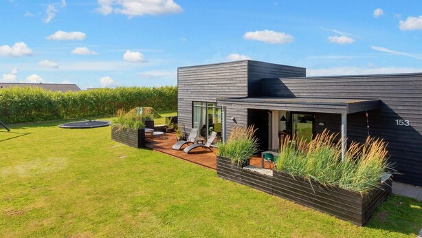 A modern house with a patio, outdoor seating, and a well-maintained lawn. - 5 Star Holiday Home in Lokken (Lokken)
