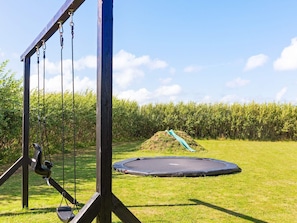 A playground with a swing set, a slide, and a trampoline.