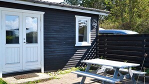 A small cabin with a white door, a window, and a picnic table outside. - 6 Person Holiday Home in Martofte (Martofte)