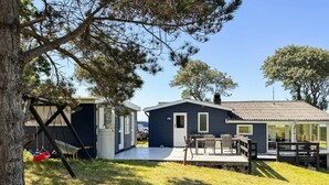 A small, two-story cabin with a deck, a swing set, and a car parked nearby. - 6 Person Holiday Home in Martofte (Martofte)