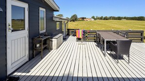 A wooden deck with a table and chairs, a bench, and a small outdoor kitchen area. - 6 Person Holiday Home in Martofte (Martofte)