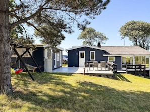 A small cabin with a deck, a swing set, and a car parked nearby. - 6 Person Holiday Home in Martofte (Martofte)