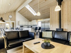 Ein modernes Wohnzimmer mit Ledersofas, einem Holztisch und Pendelleuchten.