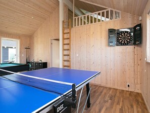 Ein Raum mit Tischtennisplatte, Dartscheibe und Billardtisch.