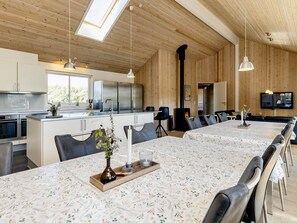 Eine moderne Küche mit Edelstahlgeräten, ein Essbereich mit einem langen Tisch und ein gemütlicher Kamin.