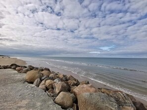 Ein Strand mit felsiger Küste und bewölktem Himmel.