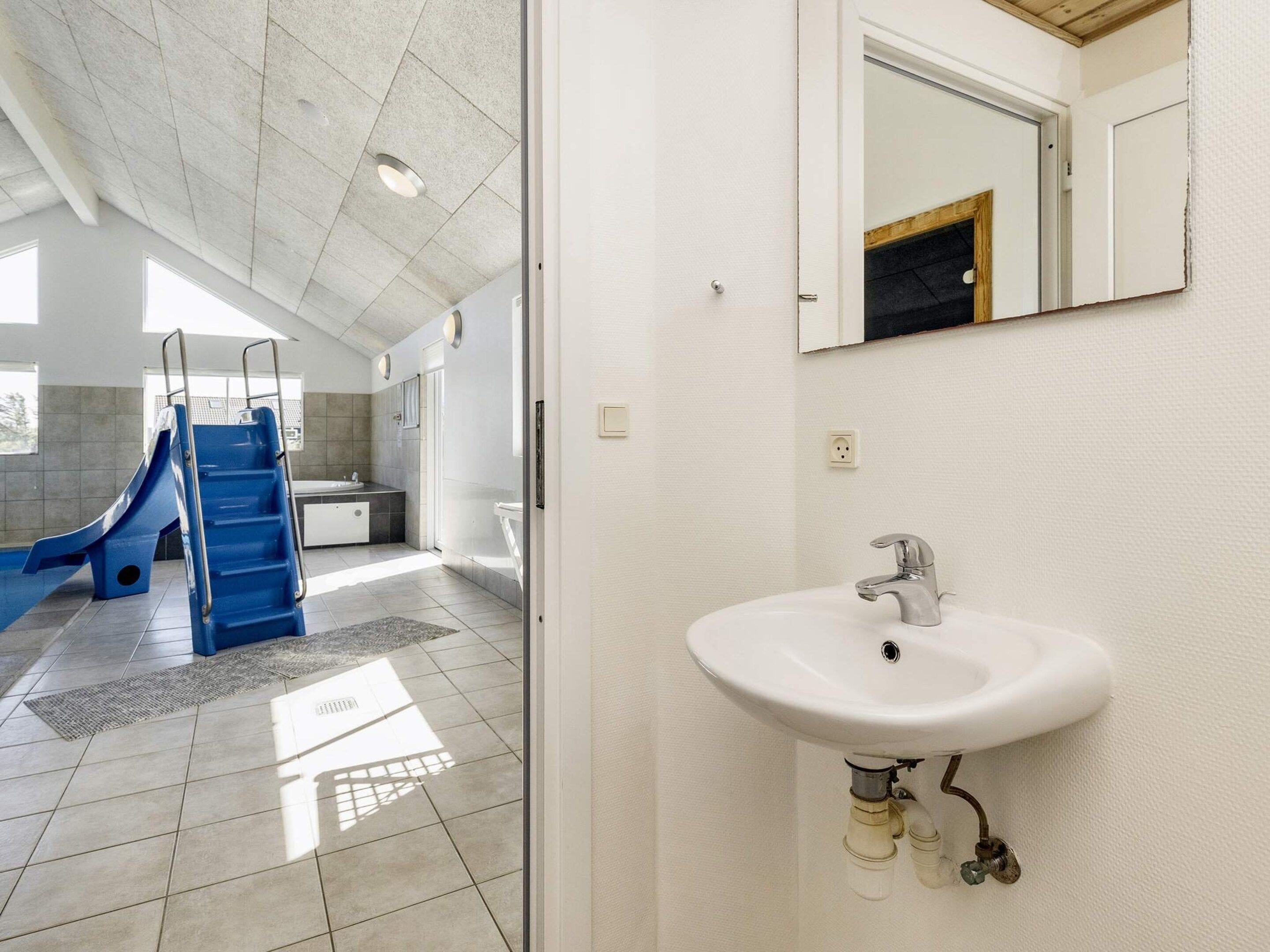 A bathroom with a white sink, a mirror, and a blue slide.