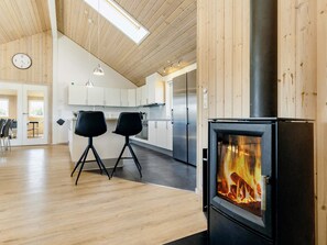 A modern kitchen with a wood-burning stove, stainless steel appliances, and a dining area with two chairs.
