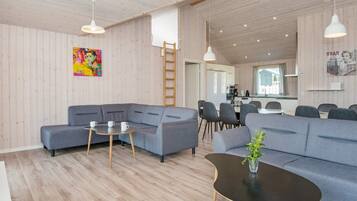 A modern living room with a sectional sofa, a round coffee table, and a dining area with chairs and a table.
