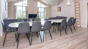 A spacious room with a large table and chairs, wooden walls, and a TV.