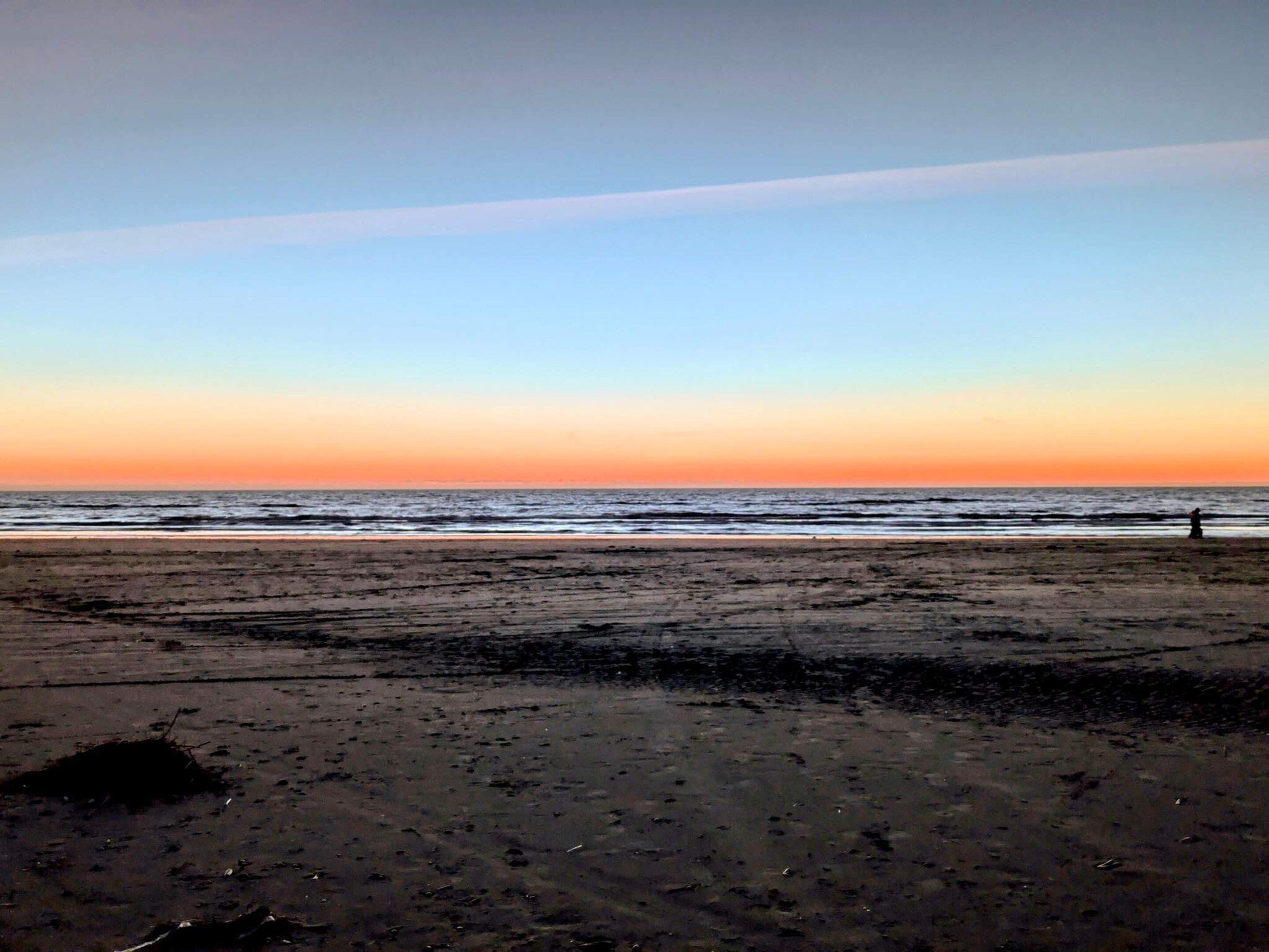 En strand med et stort sandområde og et roligt hav.