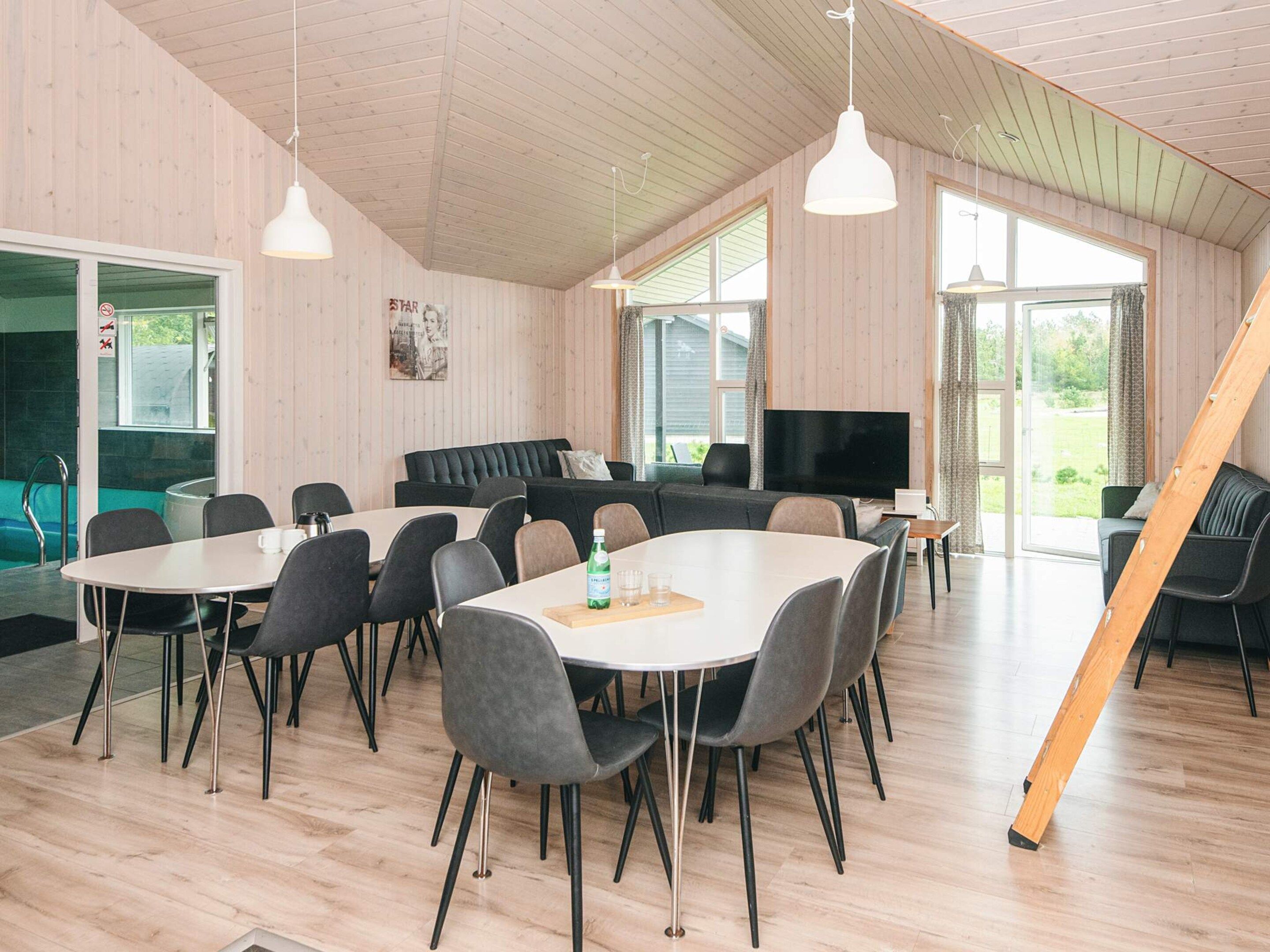 Una habitación con comedor, sofá, televisor y escalera de madera.
