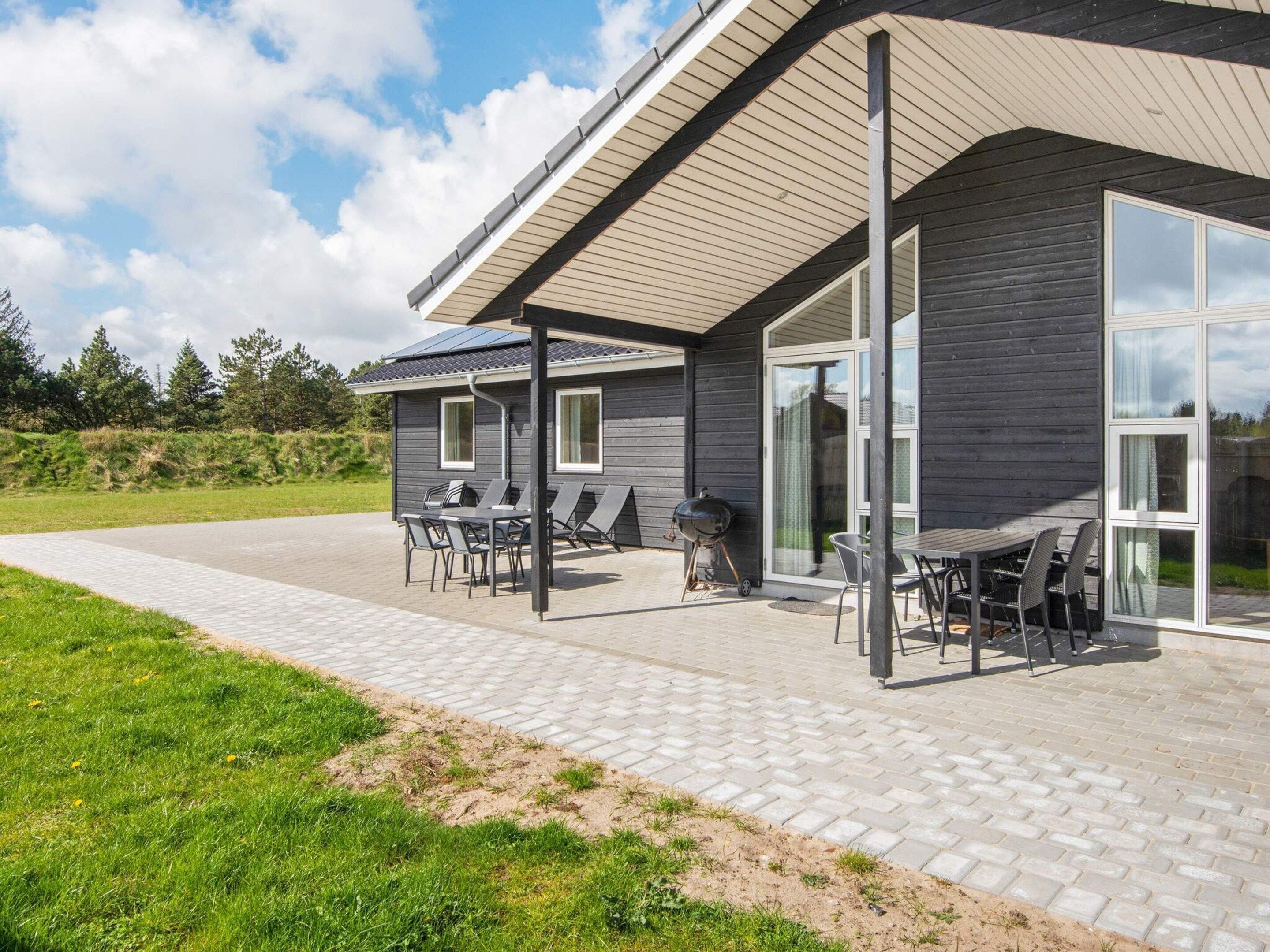 Et moderne hus med en patio med havemøbler og grill.