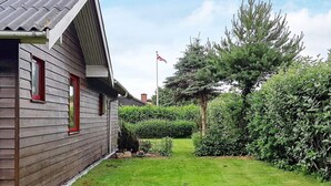 A wooden house with a sloped roof and red-framed windows.