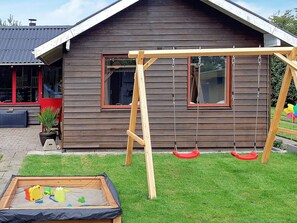 A wooden house with a swing set and a sandbox. - 6 Person Holiday Home in Hemmet (Hemmet)