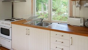 Une cuisine équipée d’une cuisinière, d’un évier et d’une fenêtre donnant sur un paysage verdoyant.