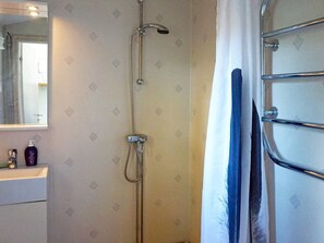 A bathroom with a shower, a mirror, and a towel rack.