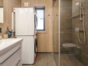 A compact bathroom with a washing machine, a shower, and a toilet. - 4 Star Holiday Home in Favang (Ringebu)